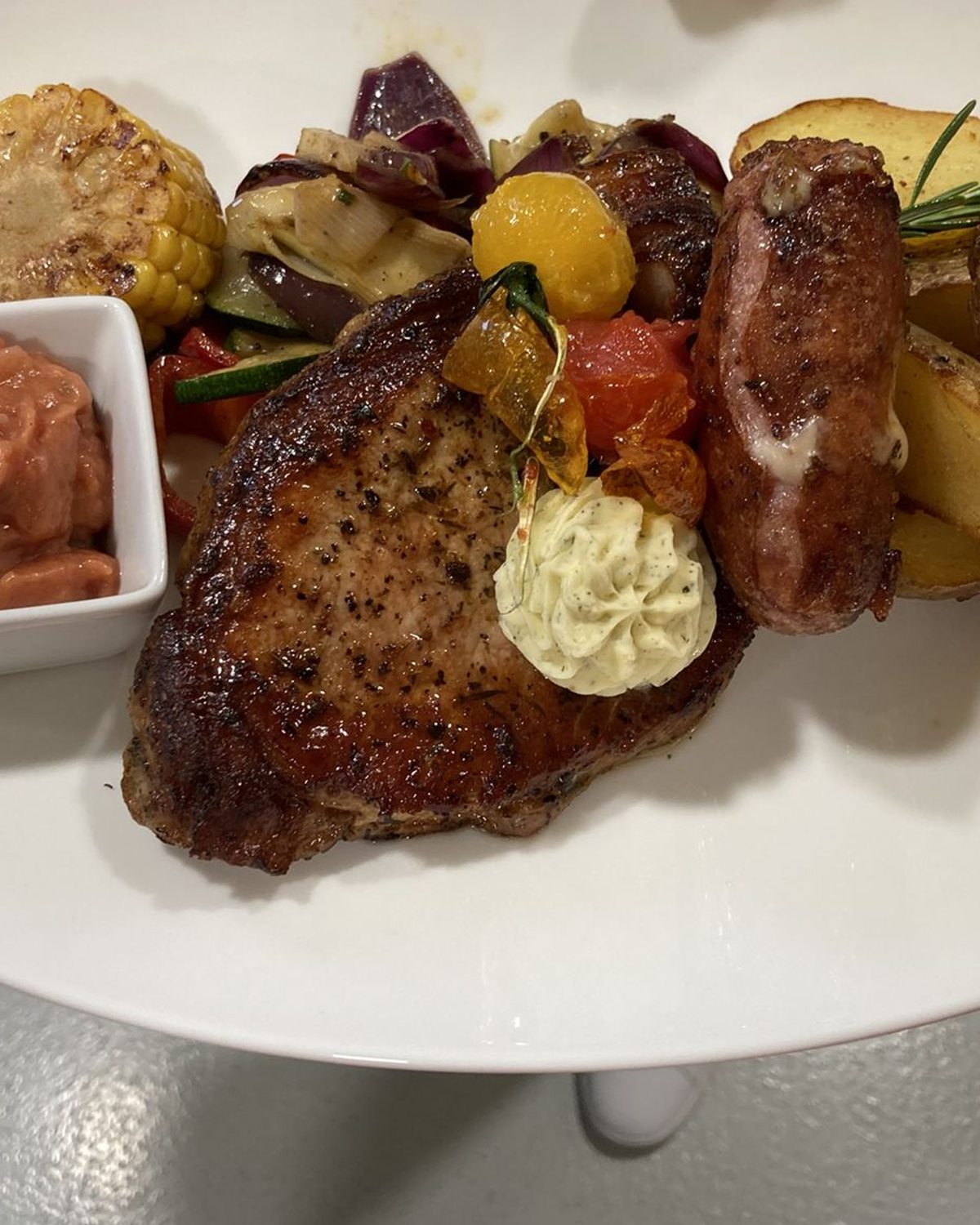 Fleischteller mit Kartoffelspalten und Kräuterbutter